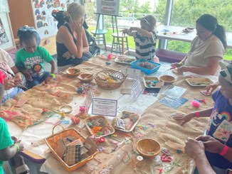Children and caregivers work together to "make their mark" with embroidery during Textile Exploration programming in LCM's Studio in the Park. Photo by L. Hémard.