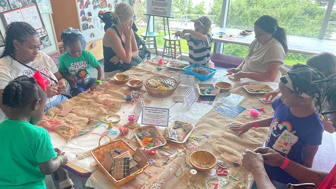 Children and caregivers work together to "make their mark" with embroidery during Textile Exploration programming in LCM's Studio in the Park. Photo by L. Hémard.